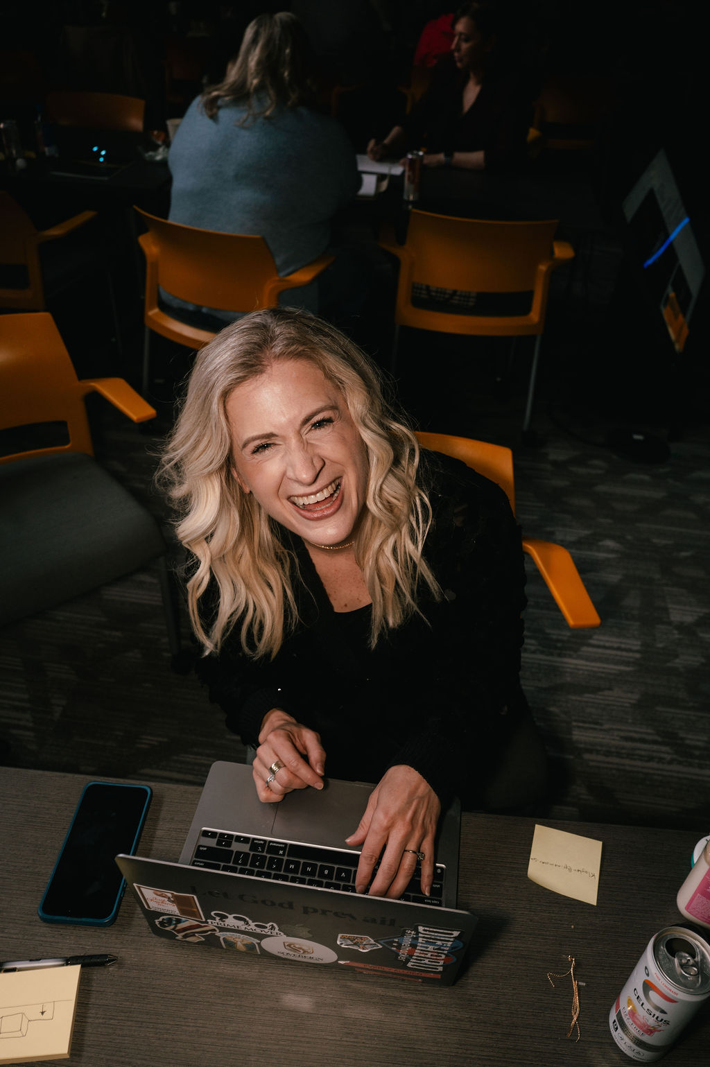 Sarah laughing while working at a laptop during the event